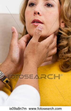 Picture - Doctor examining mid adult woman's throat, close up. Fotosearch