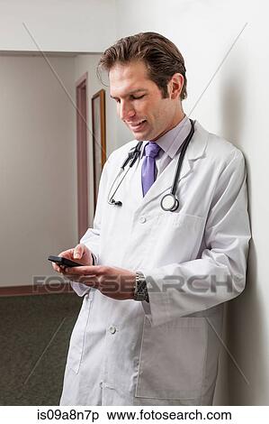 Doctor using mobile phone in hospital corridor View Large Photo Image Stock Photography - Doctor using mobile phone in hospital corridor. Fotosearch