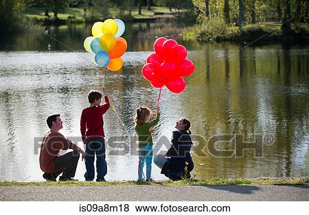 Family in front of lake with bunches of balloons View Large Photo Image Stock Photo - Family in front of lake with bunches of balloons. Fotosearch