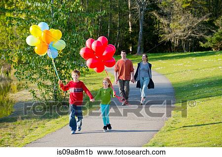 Family walking through park with bunches of balloons View Large Photo Image Stock Image - Family walking through park with bunches of balloons. Fotosearch