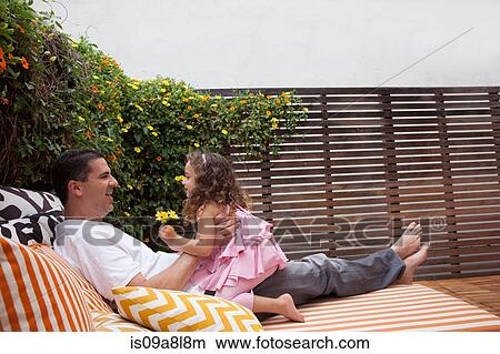 Father and daughter relaxing outdoors, girl holding flowers View Large Photo Image Picture - Father and daughter relaxing outdoors, girl holding flowers. Fotosearch