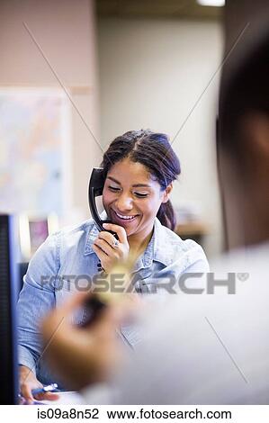 Stock Image - Female office worker on landline. Fotosearch