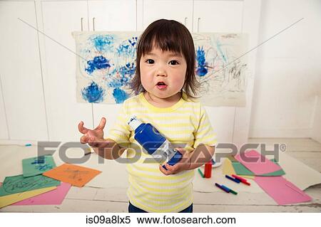 Stock Photography - Female toddler holding paint bottle. Fotosearch