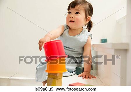 Stock Photo - Female toddler on stairs building tower. Fotosearch