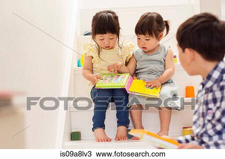 Stock Image - Female toddlers on stairs with game book. Fotosearch
