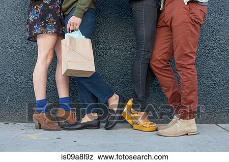 Four young adults standing by wall, low section View Large Photo Image Stock Photo - Four young adults standing by wall, low section. Fotosearch
