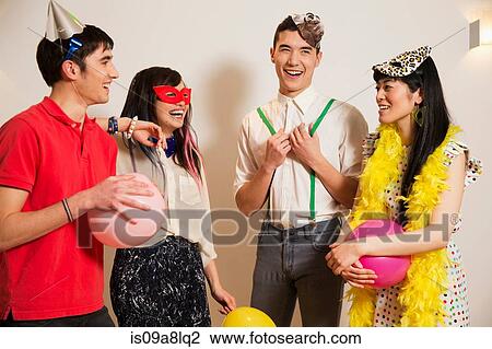 Stock Image - Friends at a party with balloons, studio shot. Fotosearch