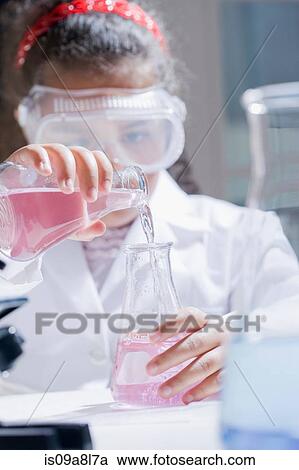 Stock Image - Girl pouring chemicals into conical flask. Fotosearch