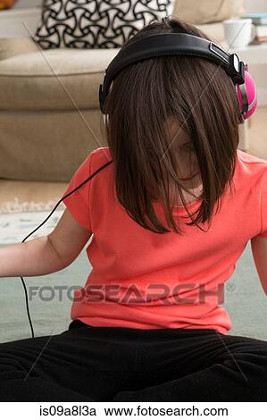Stock Image - Girl wearing headphones, looking down. Fotosearch
