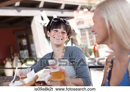 Girlfriends having drinks in outdoor cafe, smiling View Large Photo Image Stock Photograph - Girlfriends having drinks in outdoor cafe, smiling. Fotosearch