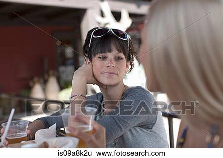 Girlfriends having drinks in outdoor cafe, smiling View Large Photo Image Stock Photograph - Girlfriends having drinks in outdoor cafe, smiling. Fotosearch