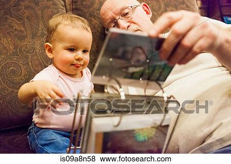 Grandfather and granddaughter looking at photo album View Large Photo Image Stock Photo - Grandfather and granddaughter looking at photo album. Fotosearch
