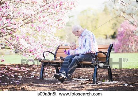 Stock Photograph - Grandfather and granddaughter together on park bench. Fotosearch