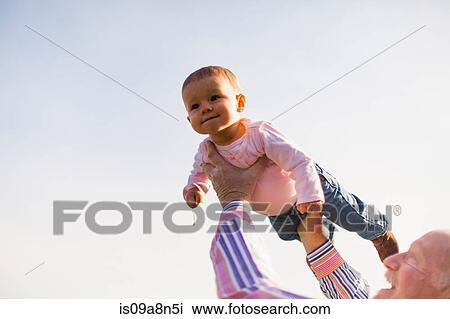 Grandfather holding up granddaughter in sunlight View Large Photo Image Stock Image - Grandfather holding up granddaughter in sunlight. Fotosearch