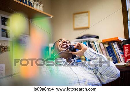 Male office worker enjoying landline conversation View Large Photo Image Picture - Male office worker enjoying landline conversation. Fotosearch