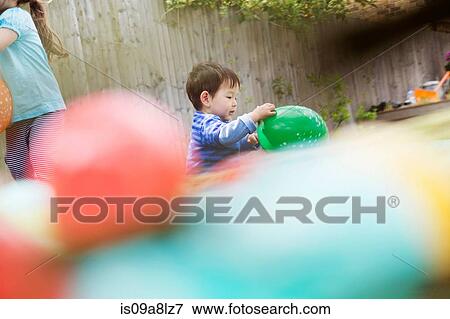 Stock Photo - Male toddler playing in garden with balloon. Fotosearch