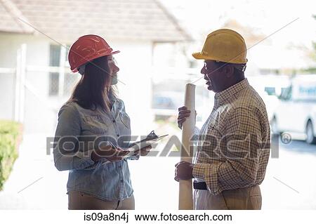 Stock Image - Man and woman meeting with blueprint and clipboard. Fotosearch