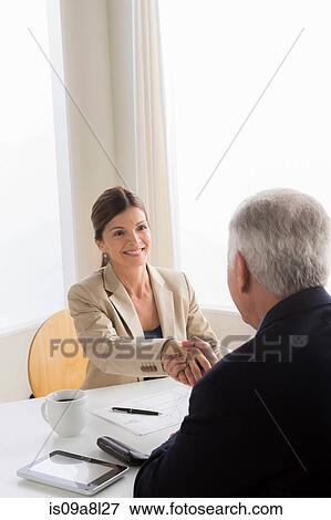 Stock Photo - Man and woman shaking hands in meeting. Fotosearch