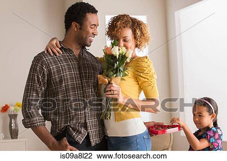 Man giving woman flowers, daughter taking chocolate View Large Photo Image Stock Image - Man giving woman flowers, daughter taking chocolate. Fotosearch