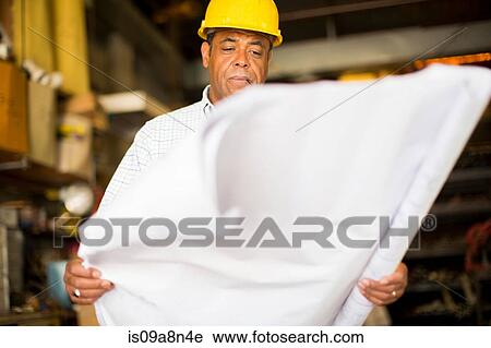 Man in warehouse holding up blueprint View Large Photo Image Stock Image - Man in warehouse holding up blueprint. Fotosearch