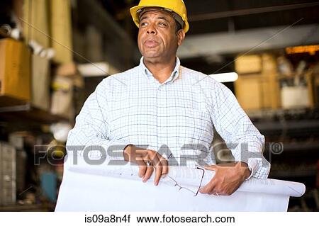 Man in warehouse rolling up blueprint View Large Photo Image Stock Image - Man in warehouse rolling up blueprint. Fotosearch