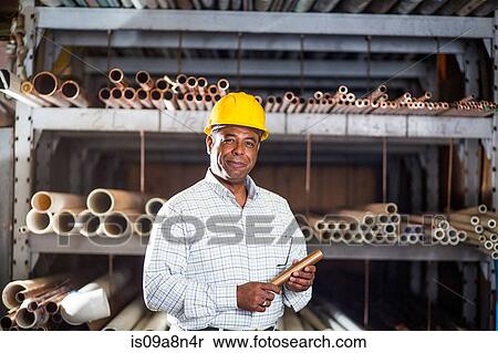 Stock Photography - Man in warehouse with copper pipe. Fotosearch