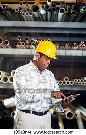 Stock Photograph - Man in warehouse with digital tablet. Fotosearch