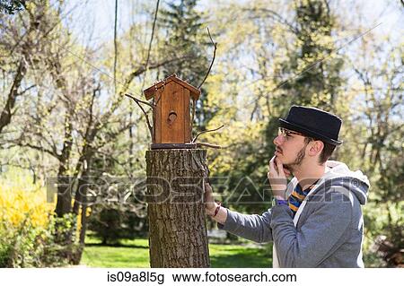 Man looking at birdhouse with hand on chin View Large Photo Image Stock Image - Man looking at birdhouse with hand on chin. Fotosearch