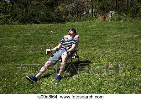 Man sitting on chair sunbathing View Large Photo Image Picture - Man sitting on chair sunbathing. Fotosearch