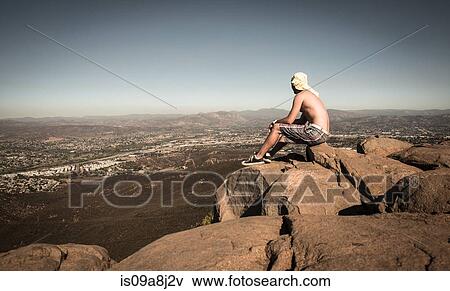 Man sitting on rock looking at view over San Diego, California, USA View Large Photo Image Stock Photo - Man sitting on rock looking at view over San Diego, California, USA. Fotosearch