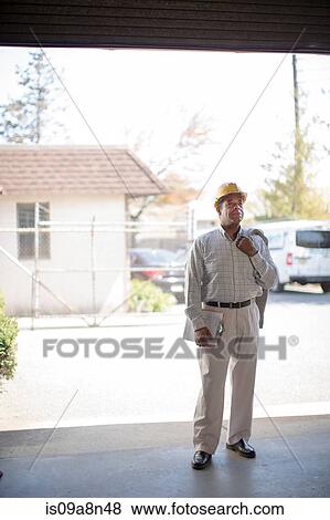 Stock Photo - Man wearing hard hat and carrying clipboard. Fotosearch