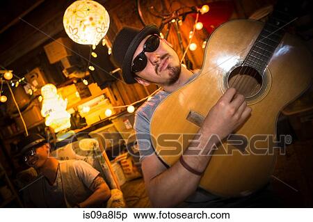 Stock Photography - Man wearing hat and sunglasses playing guitar. Fotosearch