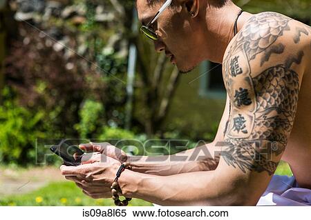 Man with tattoos using smartphone View Large Photo Image Stock Photography - Man with tattoos using smartphone. Fotosearch