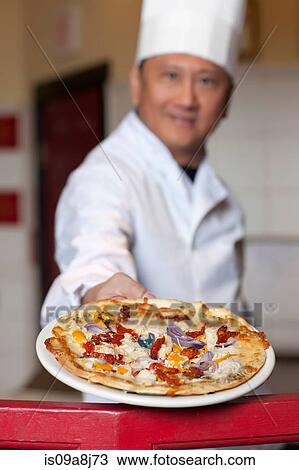 Mature chef holding fresh pizza on plate, portrait View Large Photo Image Stock Image - Mature chef holding fresh pizza on plate, portrait. Fotosearch