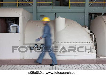 Stock Image - Mature construction worker walking through power station, blurred motion. Fotosearch