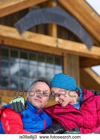 Stock Image - Mature man and young woman relaxing together in ski resort. Fotosearch