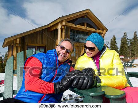 Stock Photo - Mature man and young woman relaxing together in ski resort, portrait. Fotosearch