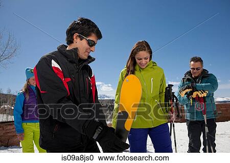 Stock Image - Mature man and young woman with ski instructors on ski slope. Fotosearch