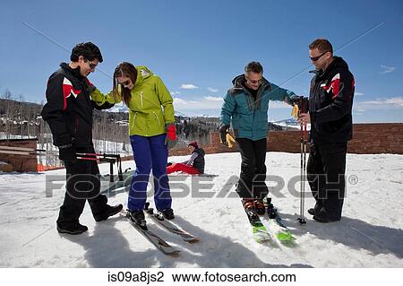 Stock Image - Mature man and young woman with ski instructors on ski slope. Fotosearch