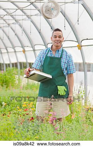 Mature man holding clipboard in garden centre, portrait View Large Photo Image Stock Image - Mature man holding clipboard in garden centre, portrait. Fotosearch