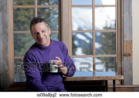 Mature man holding hot drink indoors, smiling View Large Photo Image Stock Image - Mature man holding hot drink indoors, smiling. Fotosearch
