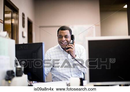 Stock Photo - Mature man in office on landline. Fotosearch