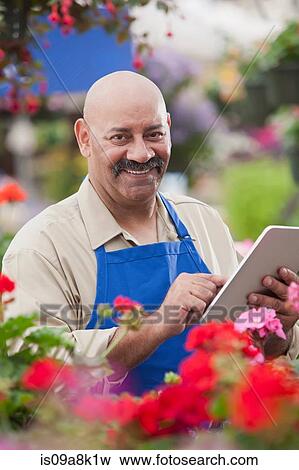 Mature man using clipboard in garden centre, portrait View Large Photo Image Stock Photo - Mature man using clipboard in garden centre, portrait. Fotosearch