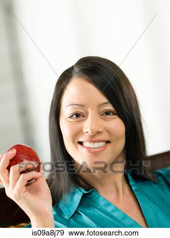 Stock Photo - Mature woman holding apple, portrait. Fotosearch