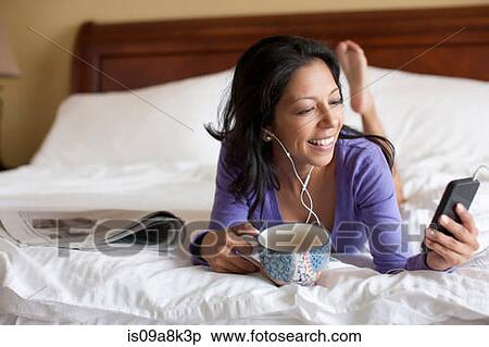 Mature woman lying on bed and listening to mp3 player, smiling View Large Photo Image Stock Photography - Mature woman lying on bed and listening to mp3 player, smiling. Fotosearch