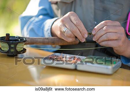 Stock Photograph - Mature woman preparing bait for fly fishing, close up. Fotosearch
