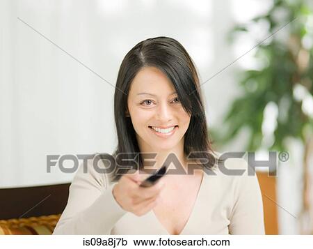 Stock Image - Mature woman using remote control, portrait. Fotosearch