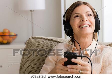 Mature woman wearing headphones listening to music View Large Photo Image Stock Image - Mature woman wearing headphones listening to music. Fotosearch