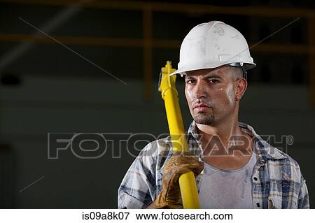 Mid adult construction worker wearing hard hat and holding tool, portrait View Large Photo Image Stock Photo - Mid adult construction worker wearing hard hat and holding tool, portrait. Fotosearch