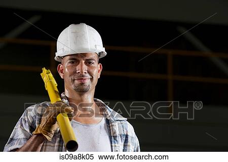 Mid adult construction worker wearing hard hat and holding tool, portrait View Large Photo Image Stock Photography - Mid adult construction worker wearing hard hat and holding tool, portrait. Fotosearch
